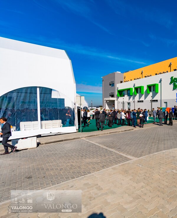 Edifício moderno com pessoas em fila, céu azul e decoração colorida.