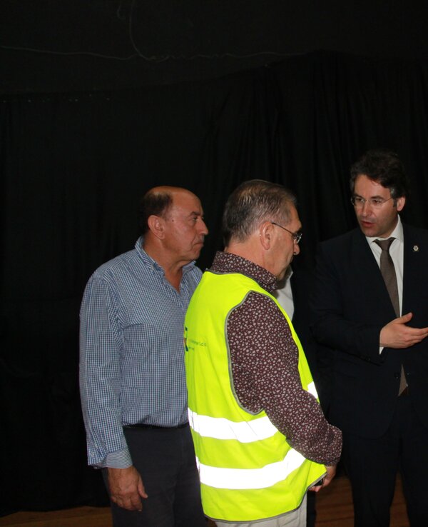 Grupo de pessoas em conversa, algumas com coletes de segurança e pastas.