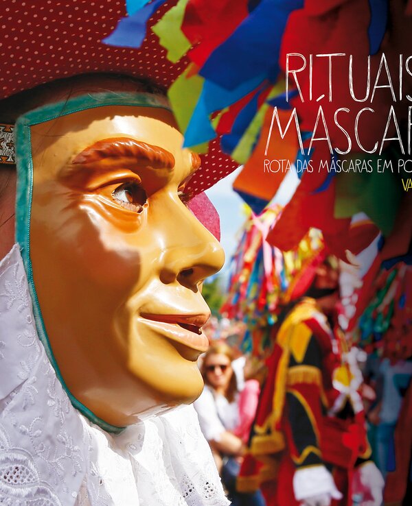 Pessoa com traje tradicional em meio a máscaras coloridas em Valongo.