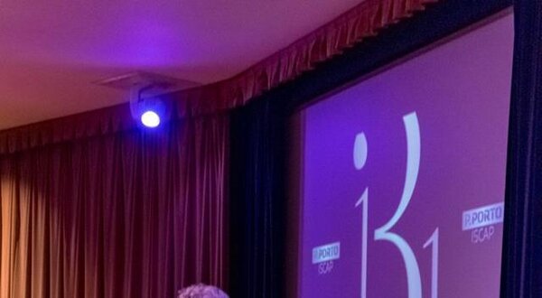 Homem em fato a apresentar num evento, com um ecrã ao fundo a dizer '31 anos'.