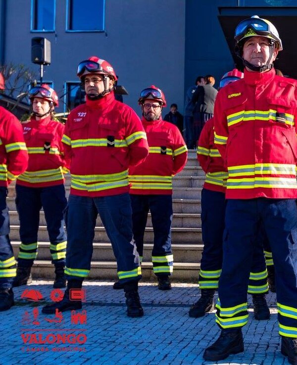 Grupo de bombeiros em uniforme vermelho e amarelo, em formação.