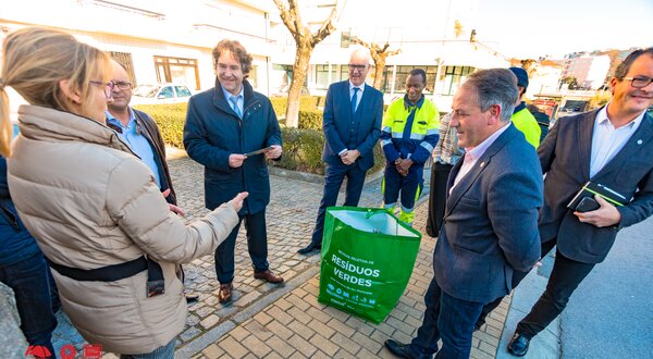 Grupo de pessoas a discutir sobre resíduos verdes, com um saco verde ao centro.