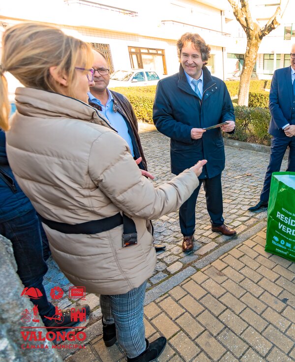 Grupo de pessoas a discutir sobre resíduos verdes, com um saco verde ao centro.