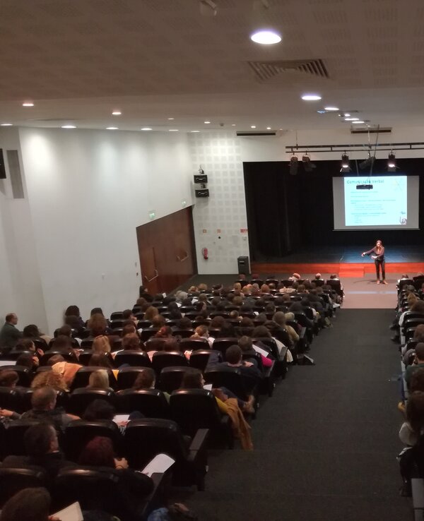 Uma sala cheia de pessoas a assistir a uma apresentação no palco.