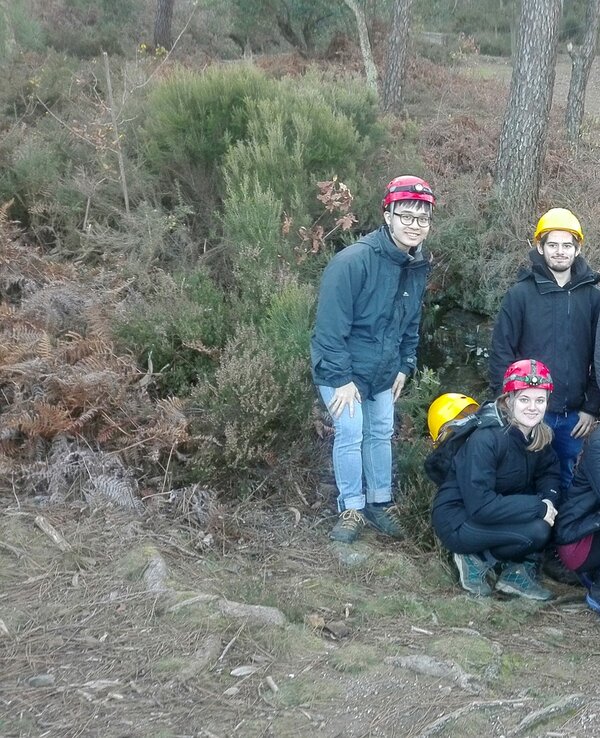 Grupo de nove pessoas em ambiente natural, usando capacetes amarelos e vermelhos.