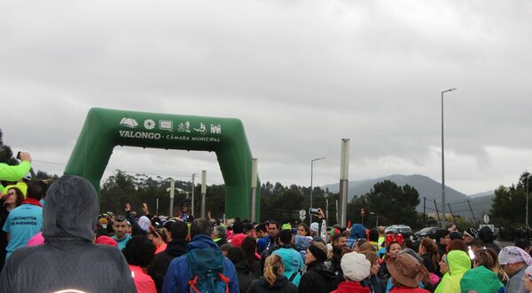 Multidão reunida sob um arco verde de partida em Valongo, dia nublado.