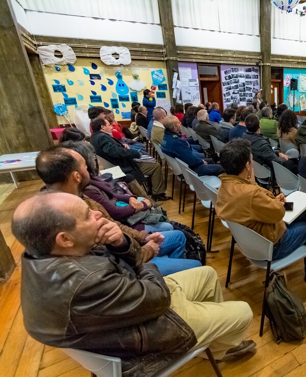 Público atento a uma apresentação em sala com decoração colorida.