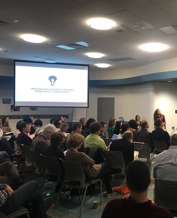 Palestra com público atento na Arizona State University, apresentador em destaque.