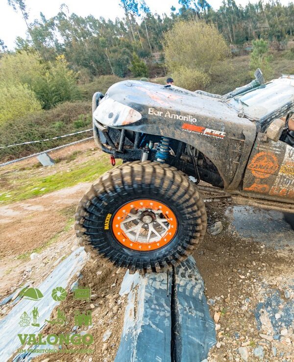 Veículo todo-o-terreno a subir uma rampa de terra, com pneus grandes e sujos.