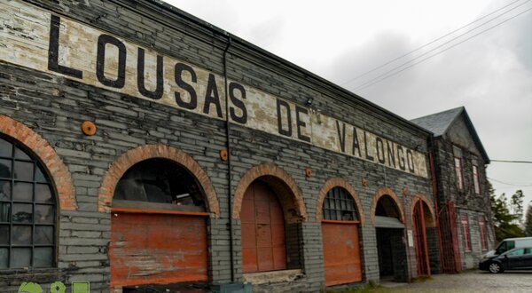Fachada de um armazém antigo com a inscrição 'LOUSAS DE VALONGO'.