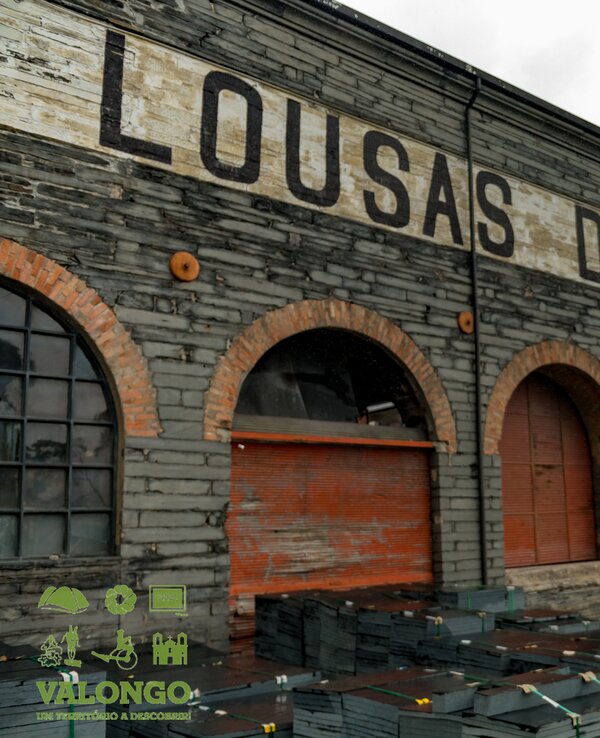 Fachada de um armazém antigo com a inscrição 'LOUSAS DE VALONGO'.