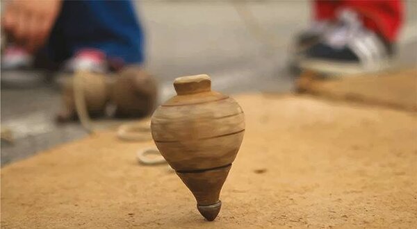 Imagem de um pião em cima de uma superfície de terra, com datas de eventos.