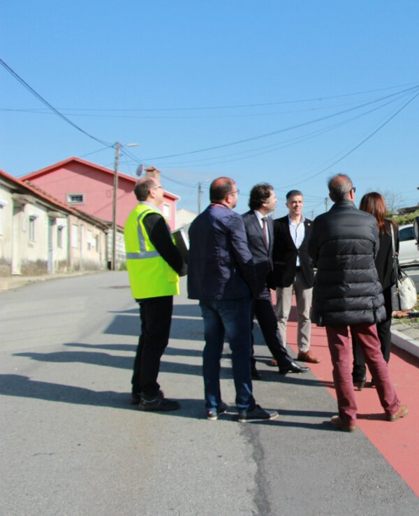 Grupo de pessoas a observar um painel informativo numa rua.
