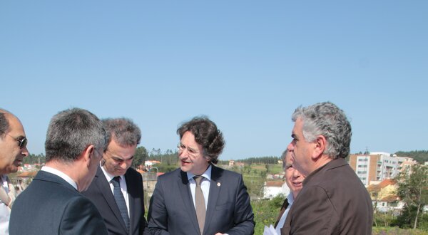 Grupo de homens a discutir um projeto ao ar livre, com plantas na mão.