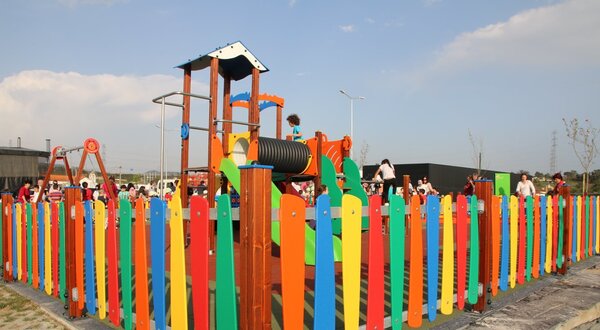 Parque infantil colorido com cercas vibrantes e crianças a brincar.