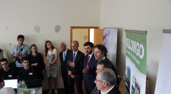 Grupo de pessoas em uma apresentação, com banners ao fundo.