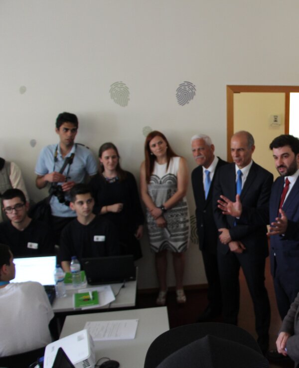 Grupo de pessoas em uma apresentação, com banners ao fundo.