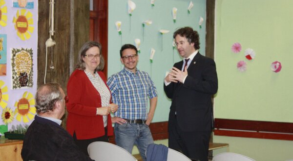 Quatro pessoas conversam em um ambiente decorado com flores de papel.