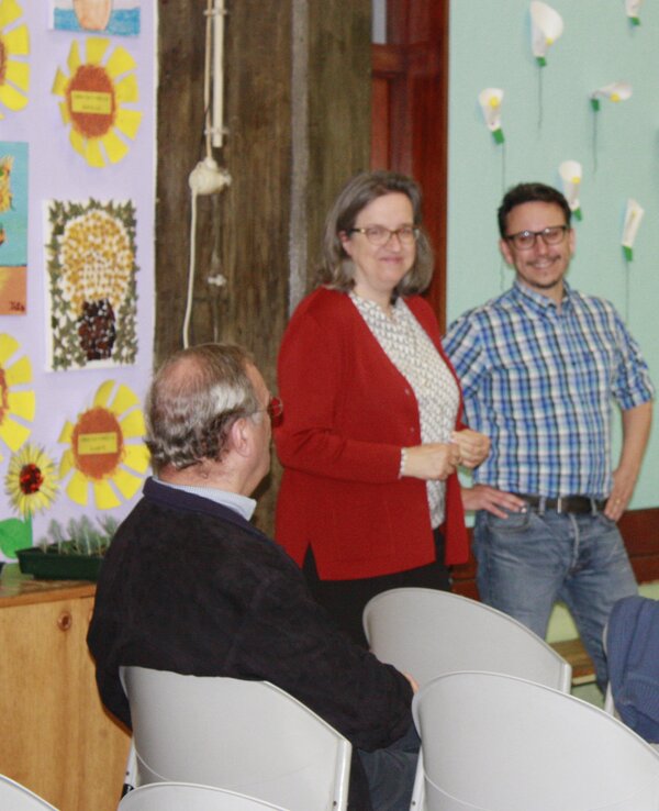 Quatro pessoas conversam em um ambiente decorado com flores de papel.
