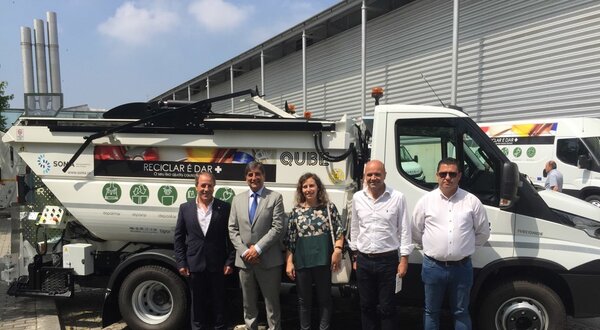Grupo de pessoas posando ao lado de um camião de reciclagem.