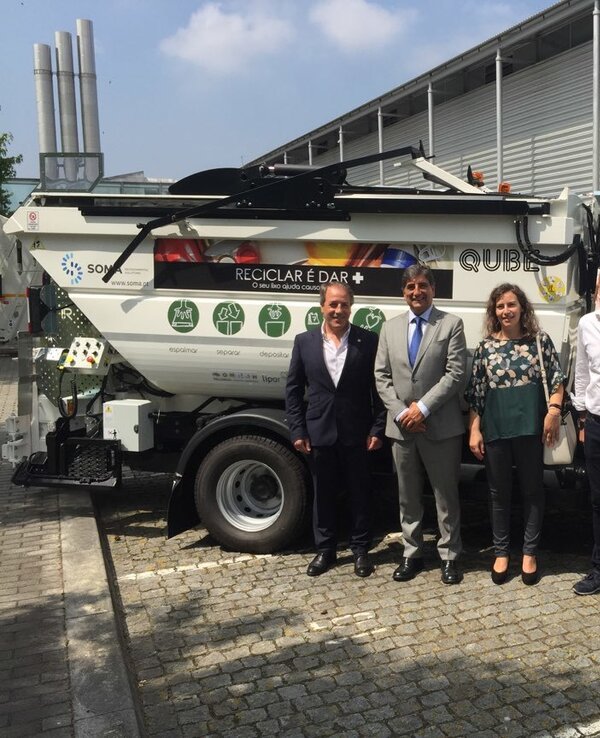 Grupo de pessoas posando ao lado de um camião de reciclagem.