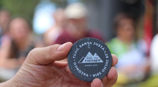 Uma mão segura uma medalha de finisher do evento T.Kail Santa Justa 2018.
