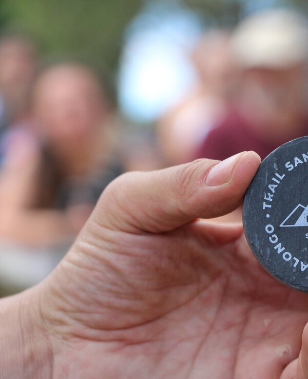 Uma mão segura uma medalha de finisher do evento T.Kail Santa Justa 2018.