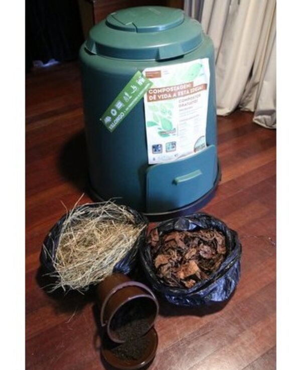 Composteira verde com materiais orgânicos e um recipiente de terra.
